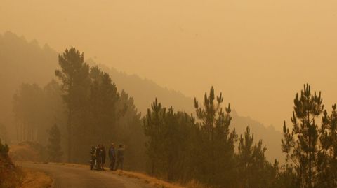 Unos vecinos, este sábado rodeados de humo en la carretera que da salida a Cereixido, Paradapiñol y Rugando hacia la N-120 y Quiroga