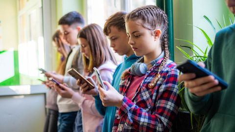 Un grupo de ni�os, consultando sus tel�fonos m�viles en una imagen de archivo.