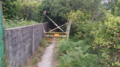 Vallado de seguridad y carteler�a de advertencia en el acceso a la playa de A Xurela, en Paderne. 