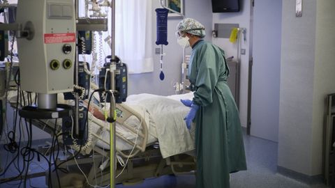 Un trabajador sanitario atiende a un paciente en una camilla de la uci  de la Cl�nica Universidad de Navarra, en Pamplona
