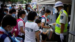 Un agente controla la temperatura de los ni�os a la entrada de una escuela china