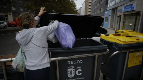 Una mujer deposita bolsas en el quinto contenedor, de tapa negra, este viernes en el barrio corus de Novo Mesoiro