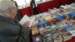Un hombre hojea vol�menes en gallego en una feria del libro.