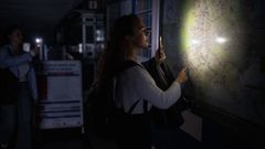 Una mujer consulta un mapa de la red de Metro con la linterna de su m�vil el d�a del apag�n