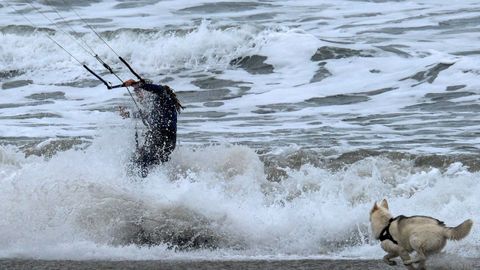 Un practicante de kitesurf y un perro en la playa de San Juan de Nieva