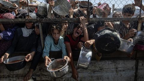 Un grupo de gazatíes desplazados a Yan Junis esperan a recibir comida en una cocina benéfica