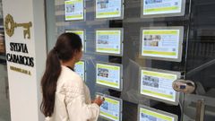 Imagen de archivo de una mujer mirando los carteles de viviendas en alquiler en una inmobiliaria de A Coru�a