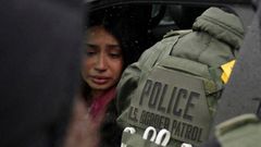 Una mujer detenida se sienta dentro de un veh�culo rodeada de agentes federales.