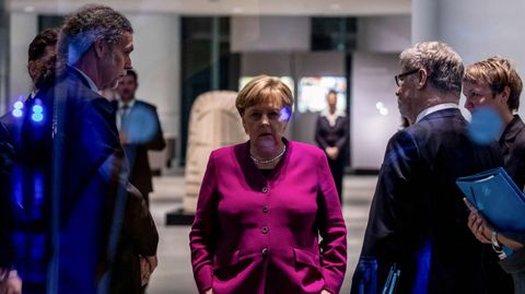 Merkel, escoltada por sus colaboradores, esperando en Berl�n el inicio de un acto