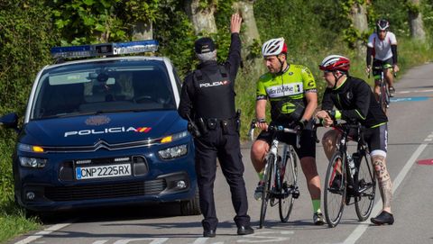 Un polica para a un grupo de ciclistas, en la falda del monte Naranco de Oviedo, en el segundo da que se permiten los paseos de adultos y el deporte individual al aire libre. EFE/Alberto Morante