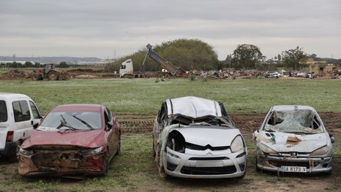 Coches apilados en un descampado de Paiporta. Al fondo, un camión descarga escombros sacados de las calles de esta localidad