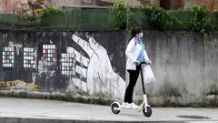 Una mujer, en patinete el�ctrico y con mascarilla en una calle de Monforte