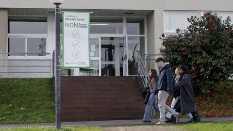 Alumnos de la UDC pasaban este vierne por delante del cartel que recuerda que no se puede fumar