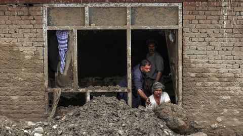 Una familia retira los escombros que la riada arrastr� hasta el interior de su casa en Charikar, ciudad de la provincia de Parwan  