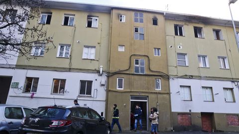 Polic�as saliendo del edificio, ante la mirada de periodistas la puerta y de vecinos en las ventanas.