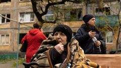 Una mujer se abriga con una manta en el exterior de su edificio, alcanzando por un  misil en la localidad de Dobropillia, en la regi�n del Domb�s