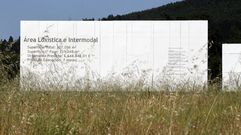 Un cartel en la entrada del puerto seco de Monforte parcialmente oculto por la maleza