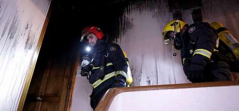 Dos bomberos se preparan para entrar en el inmueble donde se produjo el incendio.