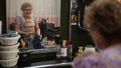 Carmen Redondo, atendiendo en su peluquería a Rita Teira, su clienta más longeva.