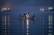 Un pesquero faena a primeras horas de ayer en la bah�a de Algeciras alejado del Pe��n.