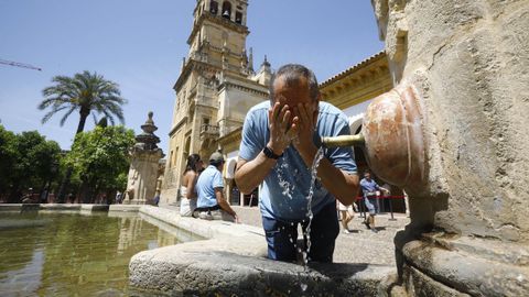 Un hombre se refresca en una de las fuentes del patio de los Naranjos de la Mezquita- Catedral de Crdoba