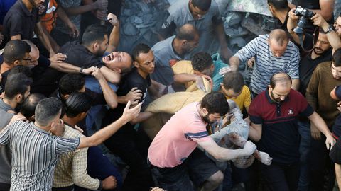 Palestinos recuperan un cuerpo tras el bombardeo del campo de refugiados de Al Magazi.