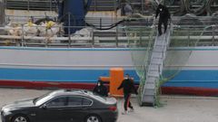 Juan Enrique Pad�n y su sobrino, Eduardo Rial, accediendo al coche tras desembarcar del Playa de Mendu��a al llegar a Terranova el 19 de febrero. Muy por detr�s, Samuel Koufie, poco despu�s de recibir la llamada del armador para, presuntamente, presionarlo y que declare lo mismo que los otros dos supervivientes. 