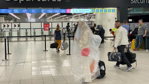 Un pasajero del aeropuerto londinense de Luton, envuelto en un pl�stico a modo de protecci�n contra el covid