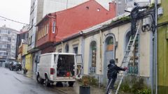 Dos operarios retiran el canal�n y las tejas del n�mero 4 de la calle Os Dur�ns para evitar accidentes despu�s de haber tapiado los accesos a la vivienda