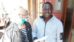 María Luisa, parte del equipo de Intervalo, entrega uno de los vales de comida a Adama, inmigrante residente en Langreo