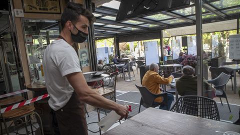 Pablo Mart�nez desinfecta una mesa dentro de su local, ya que en Noia pueden usar el 30 % del aforo interior