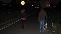 Peatones, de noche, por una de las v�as de servicio de la ronda