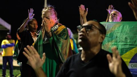 Seguidores de Bolsonaro rezan frente a la sede de la Policía Federal, donde el expresidente permanecía detenido