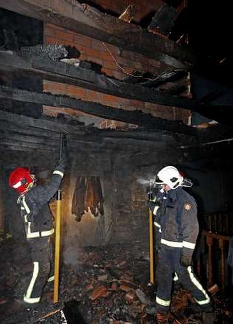 Tres bomberos trabajan en la casa tras apagar el fuego.