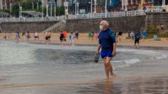Un hombre camina por la playa de San Lorenzo de Gij�n, que en un d�a nublado 