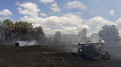 Un avi�n descarga agua sobr el incendio de Basc�s con el tractor y las bola de hierba quemados en primer t�rmino 