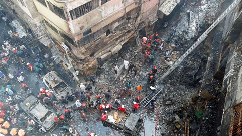 Varios bomberos inspeccionan los escombros tras el incendio declarado en el casco antiguo de Dacca, en Banglads