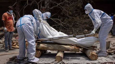 Un grupo de personas, preparando el cuerpo de una de las v�ctimas mortales del covid-19 para proceder a su cremaci�n