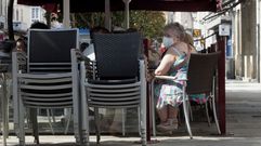 Una clienta con mascarilla en la terraza de una cafeter�a en el centro de Monforte