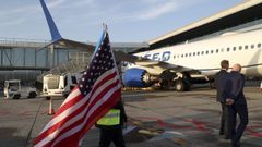 Un operario camina con la bandera de Estados Unidos hacia el avi�n de United Airlines en el estreno de la ruta entre Santiago y Newark, el 28 de mayo.