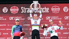 Pogacar levanta el t�tulo que le acredita como ganador de la Strade Bianche, flanqueado en el podio por Paul Seixas e Isaac del Toro.