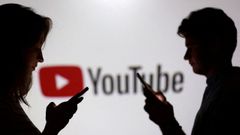 J�venes con el tel�fono frente a un cartel�n de YouTube.