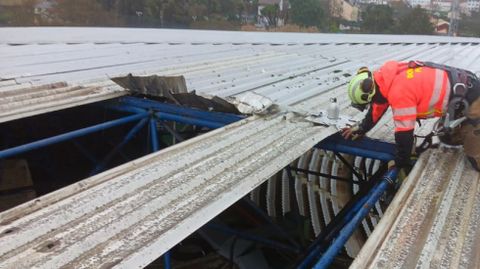 Bombero inspeccionando la cubierta del estadio de A Malata, con chapas desprendidas por el viento.