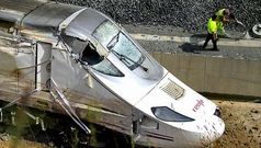 Dos operarios retirando material junto a la cabina destrozada del Alvia, dos d�as despu�s del siniestro en Angrois.