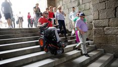 Anxo Queiruga baja con la nueva silla por las escaleras del arco hacia el Obradoiro. 