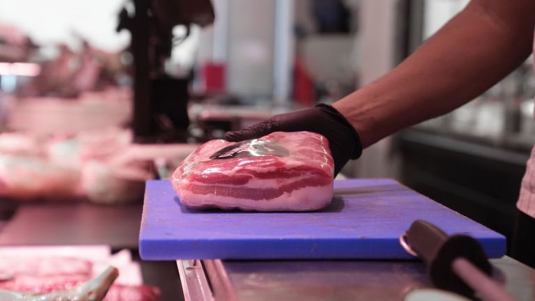 Un carnicero muetra un despiece de cerdo en un mercado de Madrid