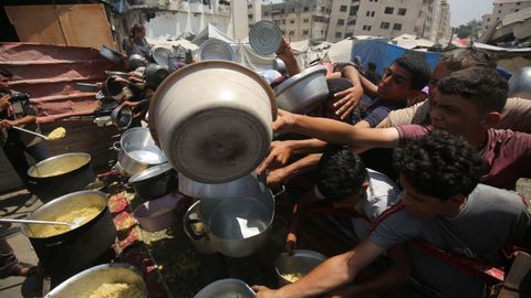 Un grupo de palestinos esperan para recibir alimentos en Gaza, aislada y bloqueada por Israel