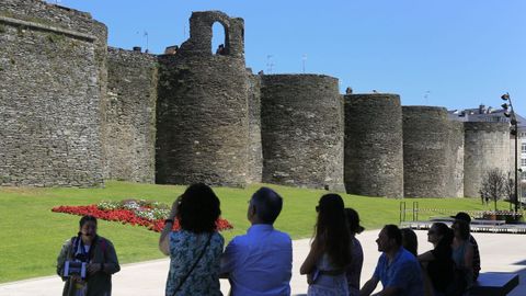 Un grupo de turistas admira la monumentalidad de la Muralla de Lugo en A Mosqueira