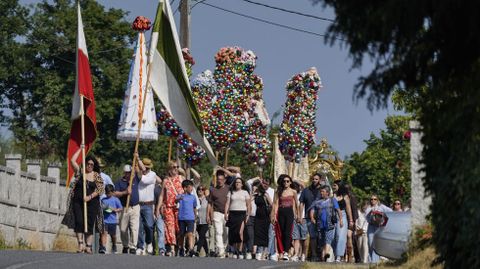 Estandartes y ramos con bolas de colores acompañan a la virgen en la procesión.