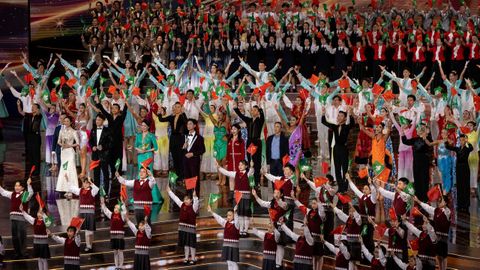 Artistas ondeando banderas de China y Macao durante un acto por el 25 aniversario.